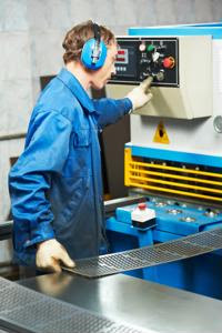 A factory worker uses a heavy machine.