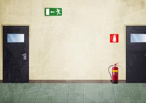 A hall with an exit sign, a fire alarm and a portable extinguisher.