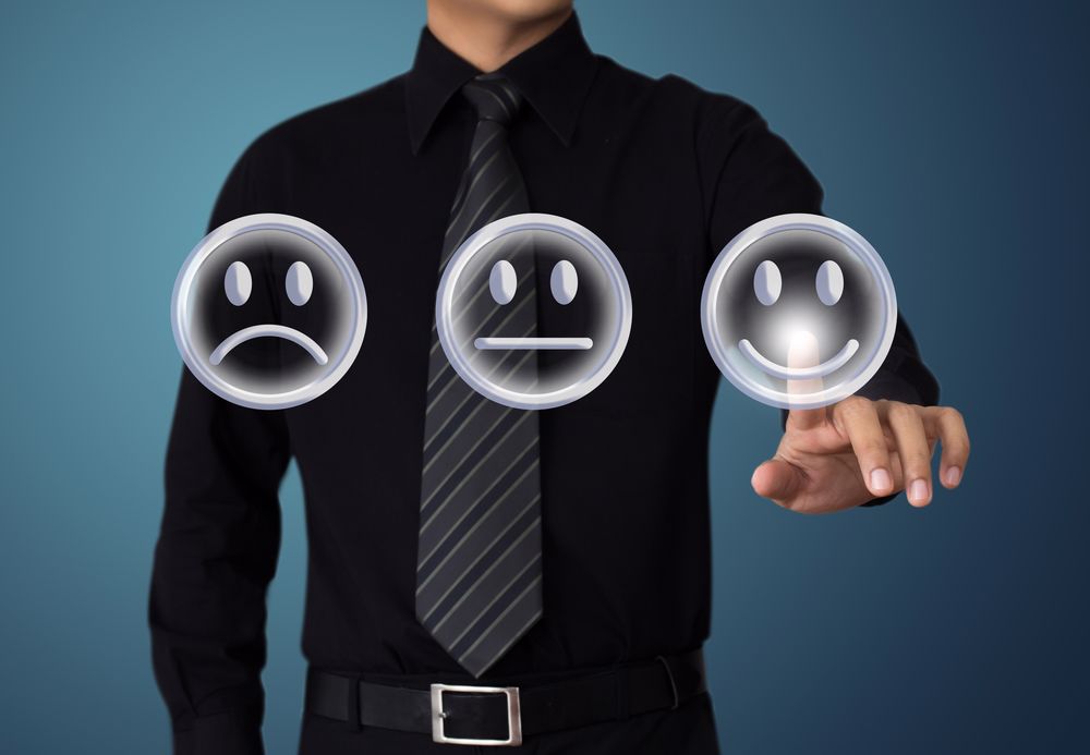man pointing at a happy face, among choice of sad, neutral and happy faces